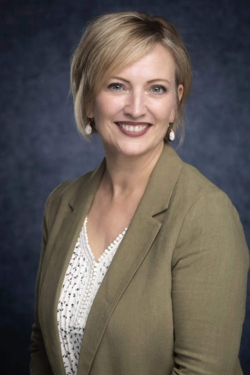 Tricia Miller professional photo woman in orange and white floral tube dress wearing black sunglasses sitting on white boat during