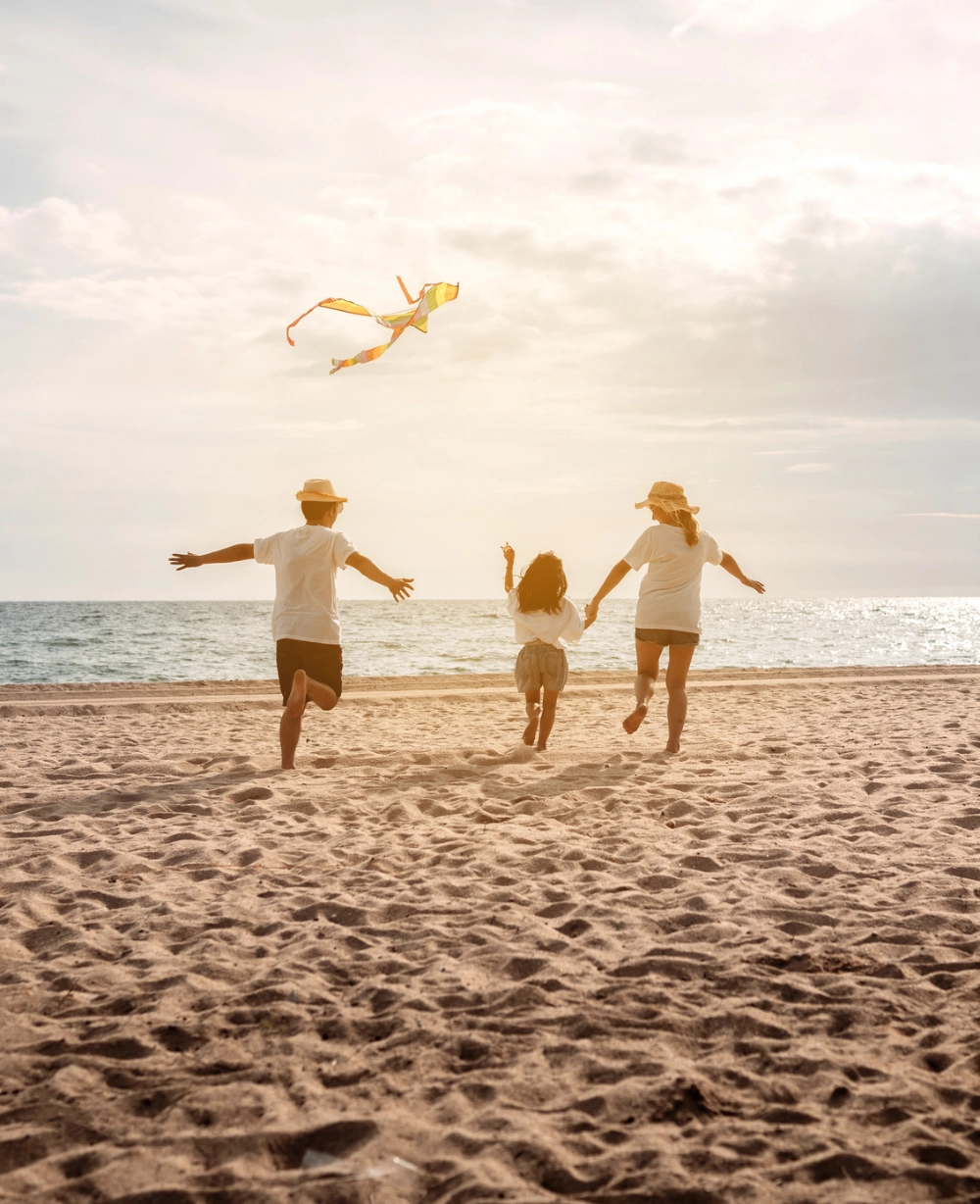 family flying a kite on the beach living a life that is bankless by design